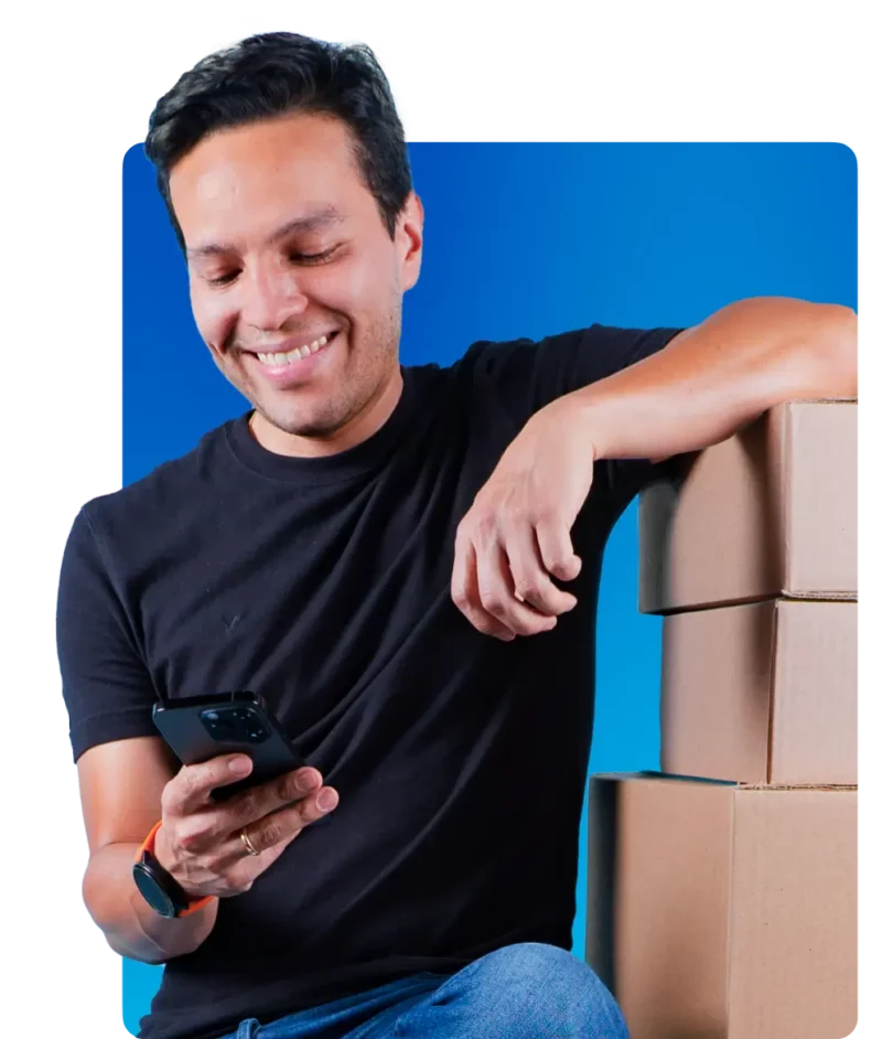 Empreendedor olhando para o celular e caixas ao lado