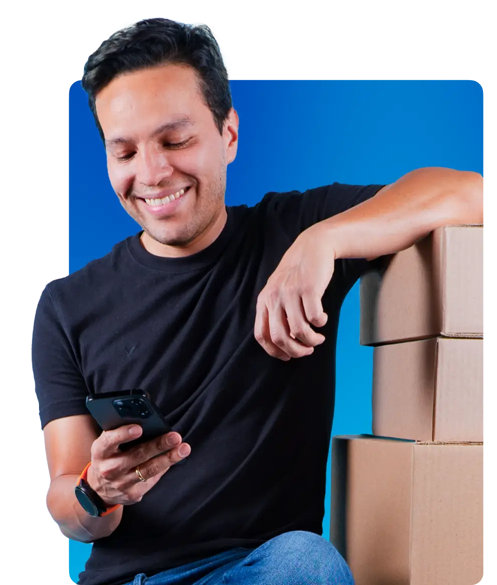 Empreendedor olhando para o celular e caixas ao lado