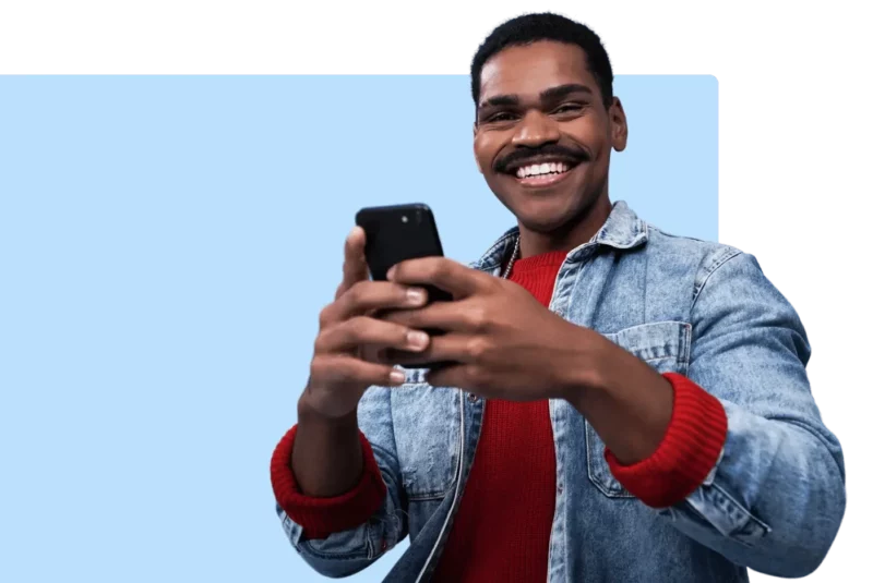 Homem negro sorrindo enquanto usa o celular