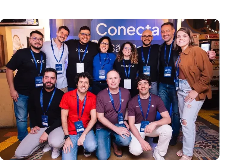 Grupo de participantes do evento Conecta posando em frente ao banner oficial