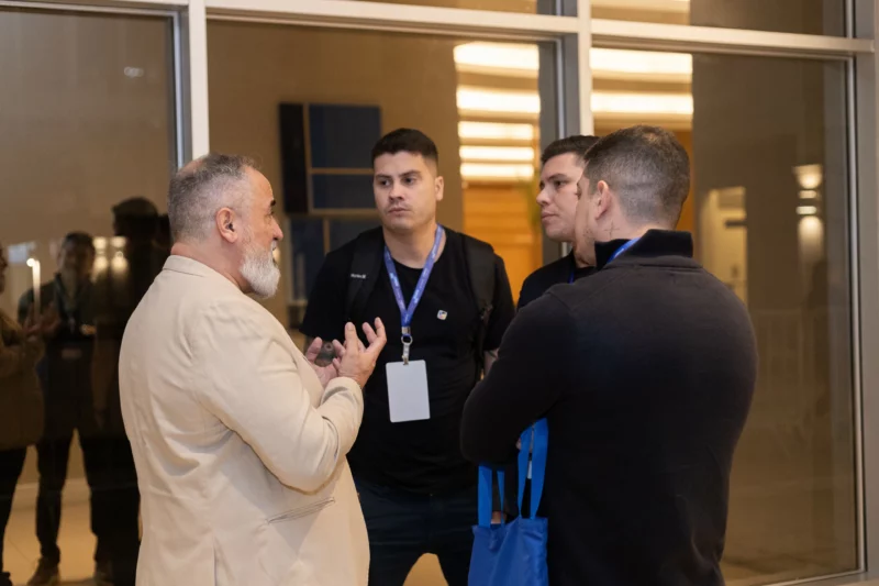 Pessoas conversando em evento corporativo com crachás visíveis