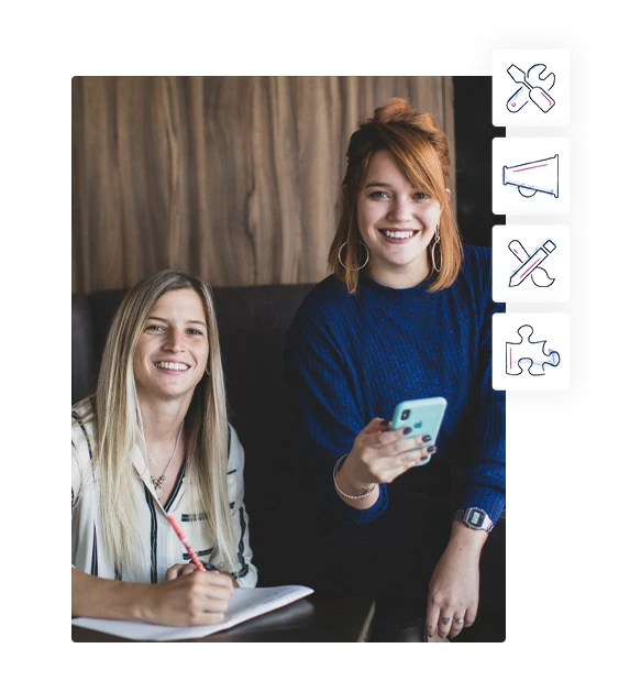 Dupla de empreendedoras sorri enquanto olha para a câmera