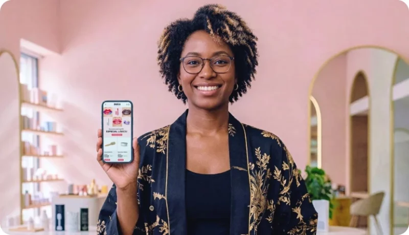 Empreendedora mostra celular com sua loja virtual